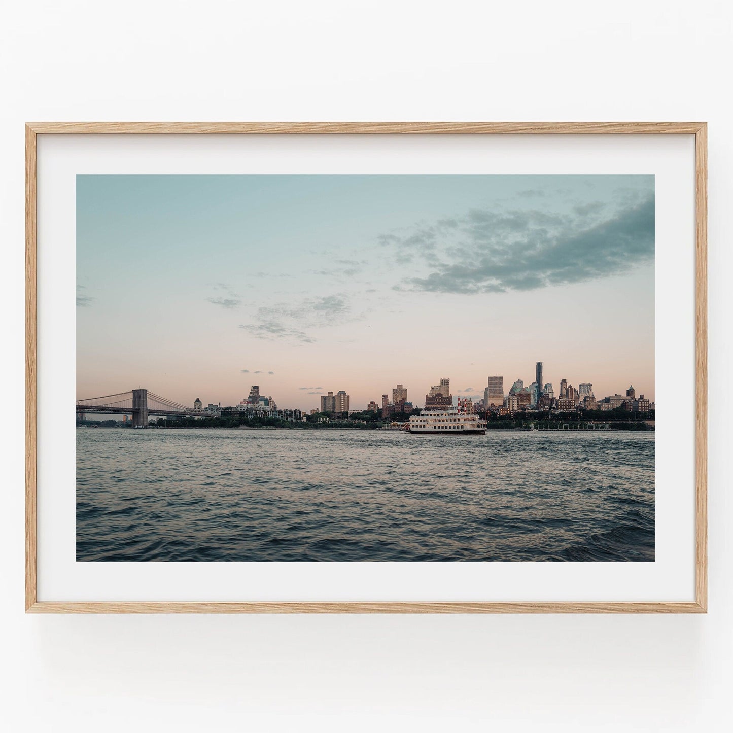 Framed photo Brooklyn Sunset featuring a city skyline at dusk with a river and bridge on the left.