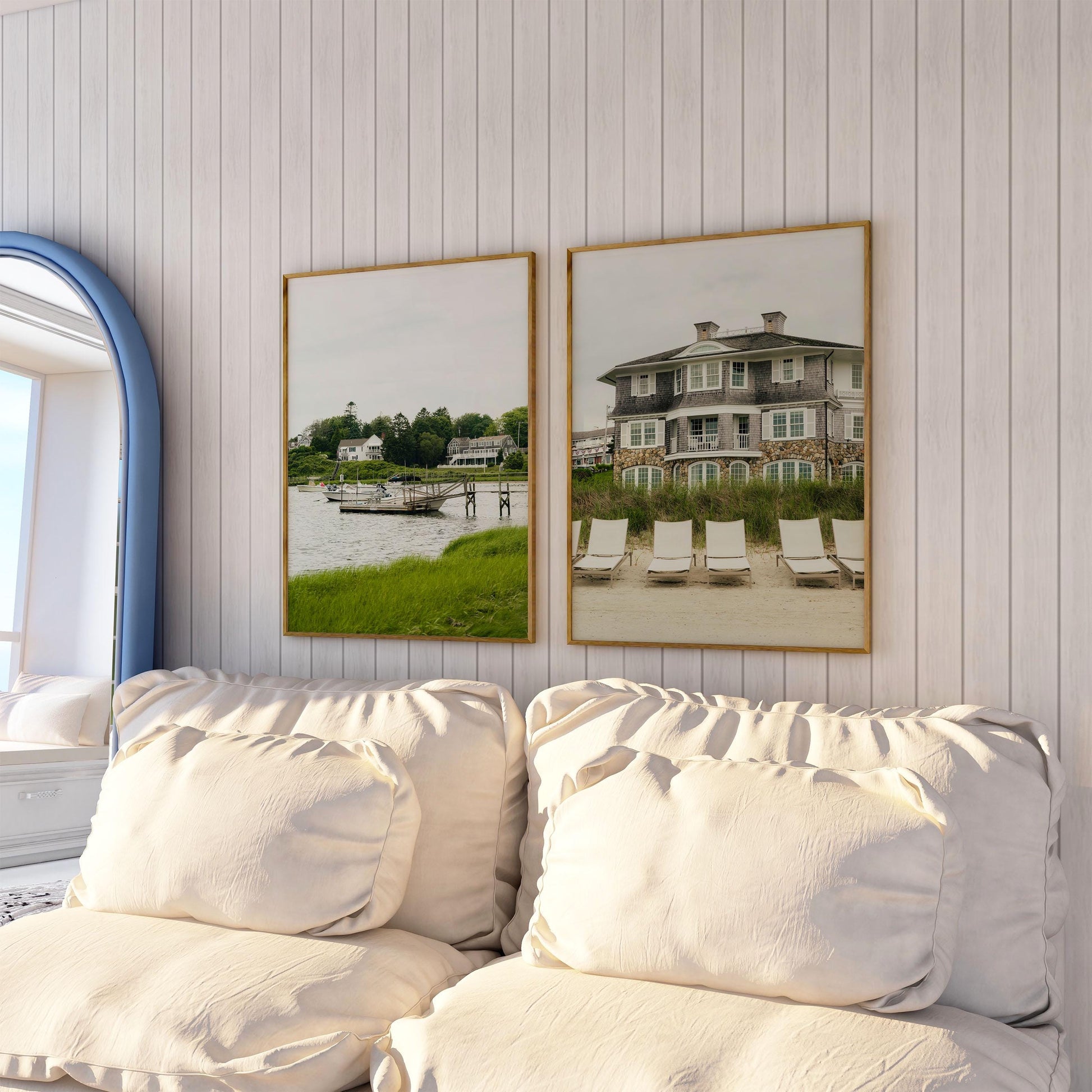 Two Cape Cod couches placed before two framed beach house paintings on a white paneled wall.