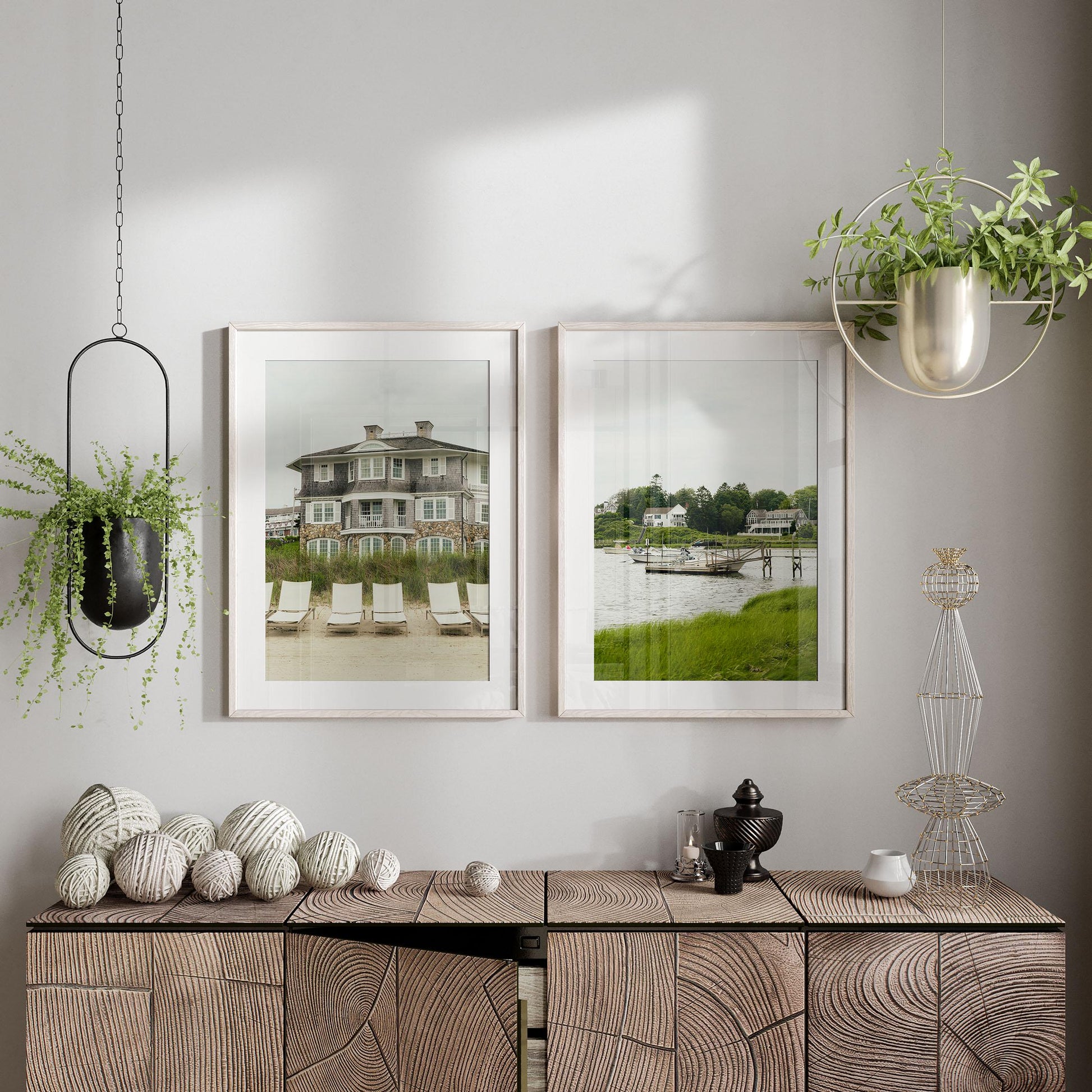 Modern interior featuring "Cape Cod - Set of 2" wall art of houses by water, hanging plants, and decorative accents.