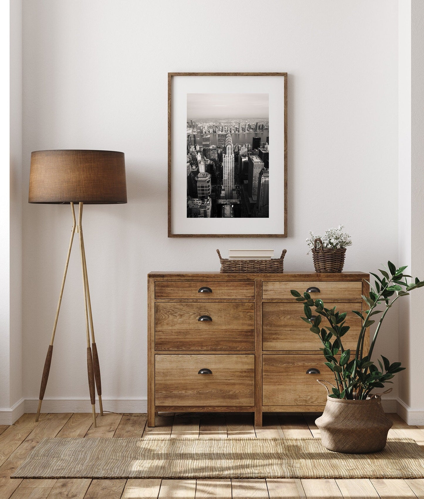 Cozy room with a wooden dresser, floor lamp, potted plant, and Chrysler Building Black and White photo on the wall.