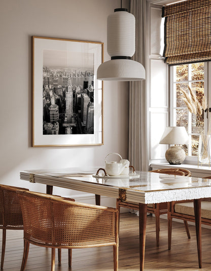 Stylish dining room with a wooden table, wicker chairs, and the Chrysler Building Black and White photo on the wall.