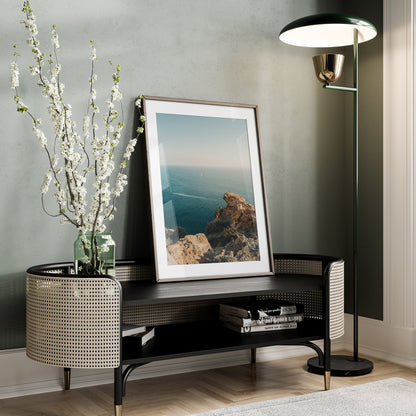 Cliffside Paradise framed photo on a bench with a vase, floor lamp, and books in a modern living room.