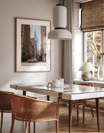 Stylish dining room with a marble table, wicker chairs, and Concrete Jungle city scene wall art featuring a yellow taxi.