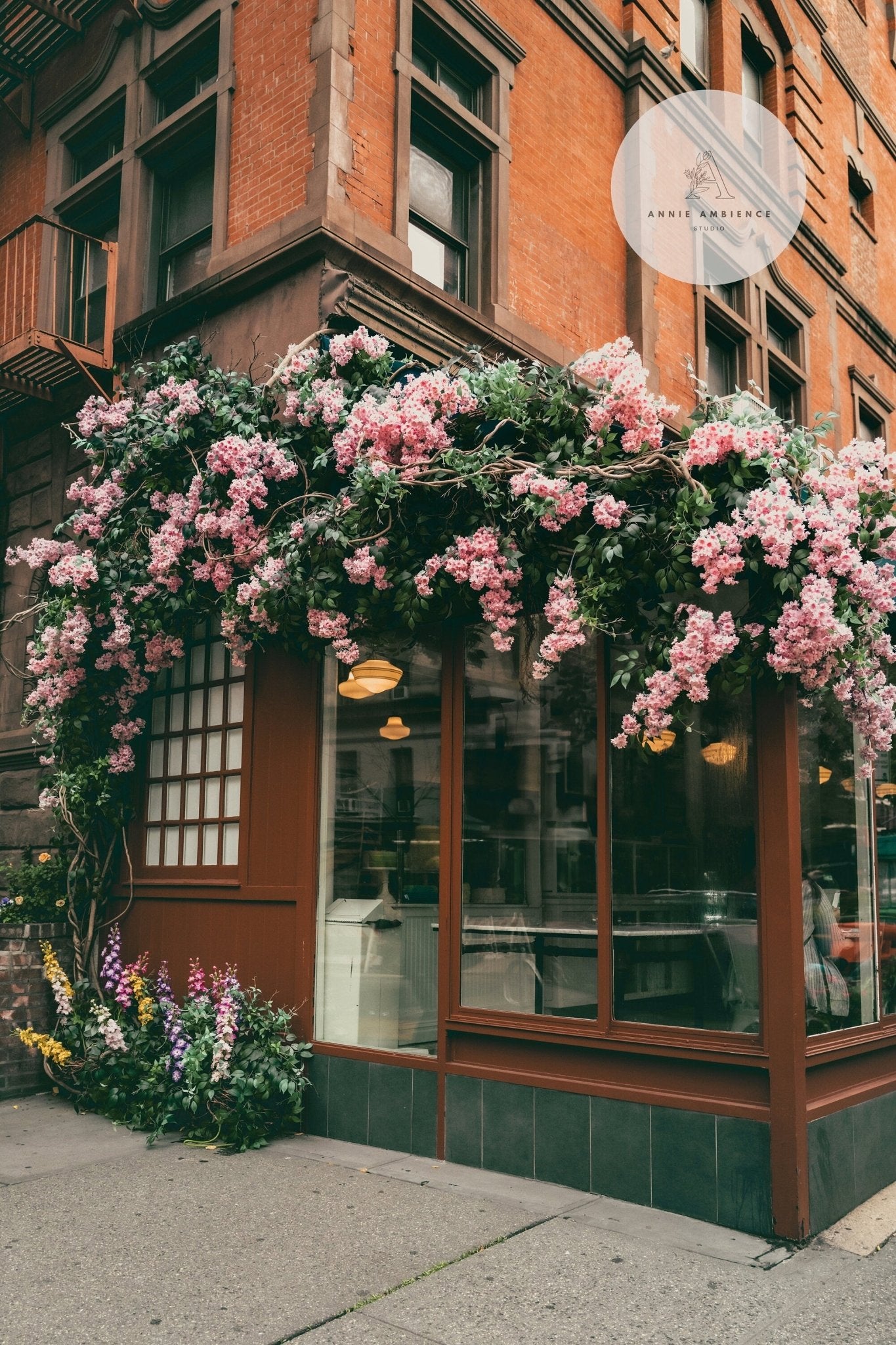 Brick building featuring Floral Cafes large pink flower arrangement above a window display.