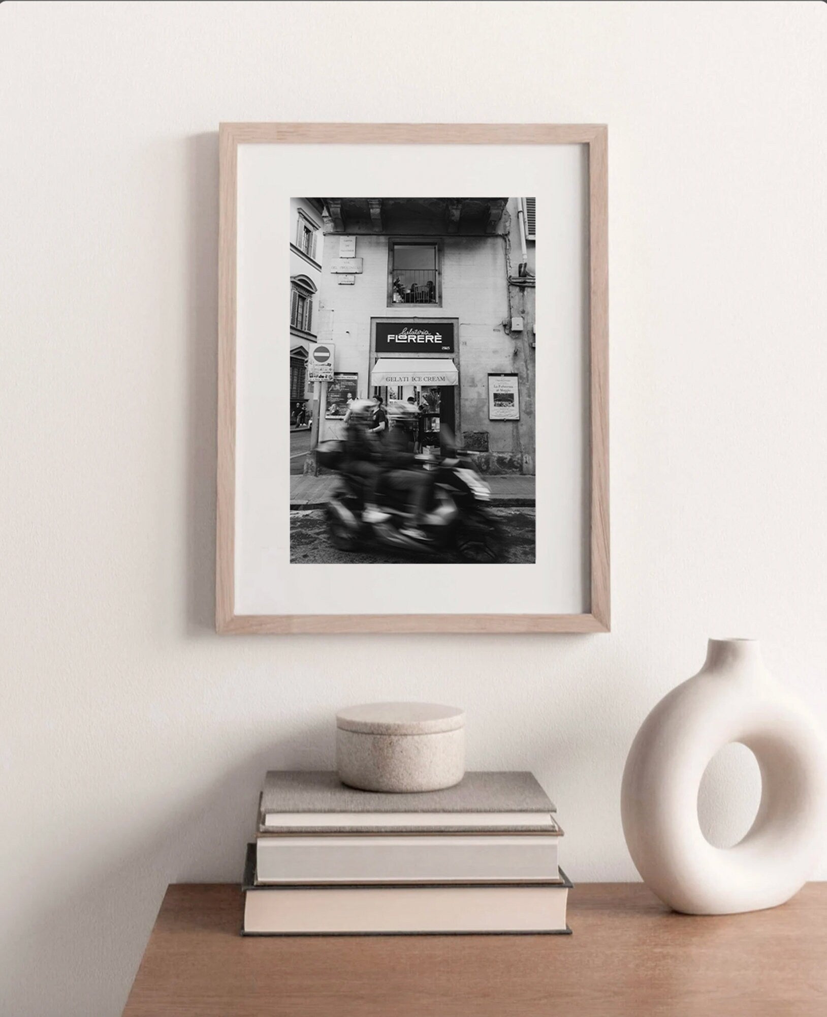 Florence Motorcycle Black and White framed photo on a minimalist shelf with decor pieces.