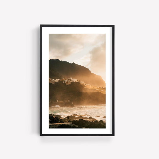 Framed photo titled Golden Garachico shows a coastal village on rocky cliffs at sunset with waves and warm sunlight.