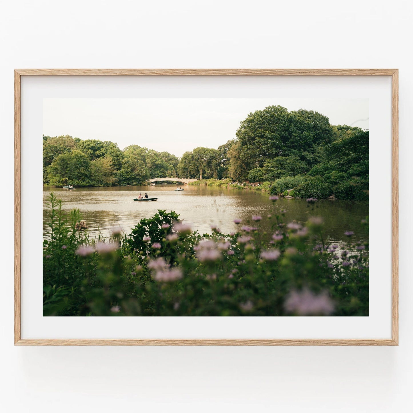 Golden Glide: A framed photo of a serene lake with a boat, lush greenery, and a distant bridge.