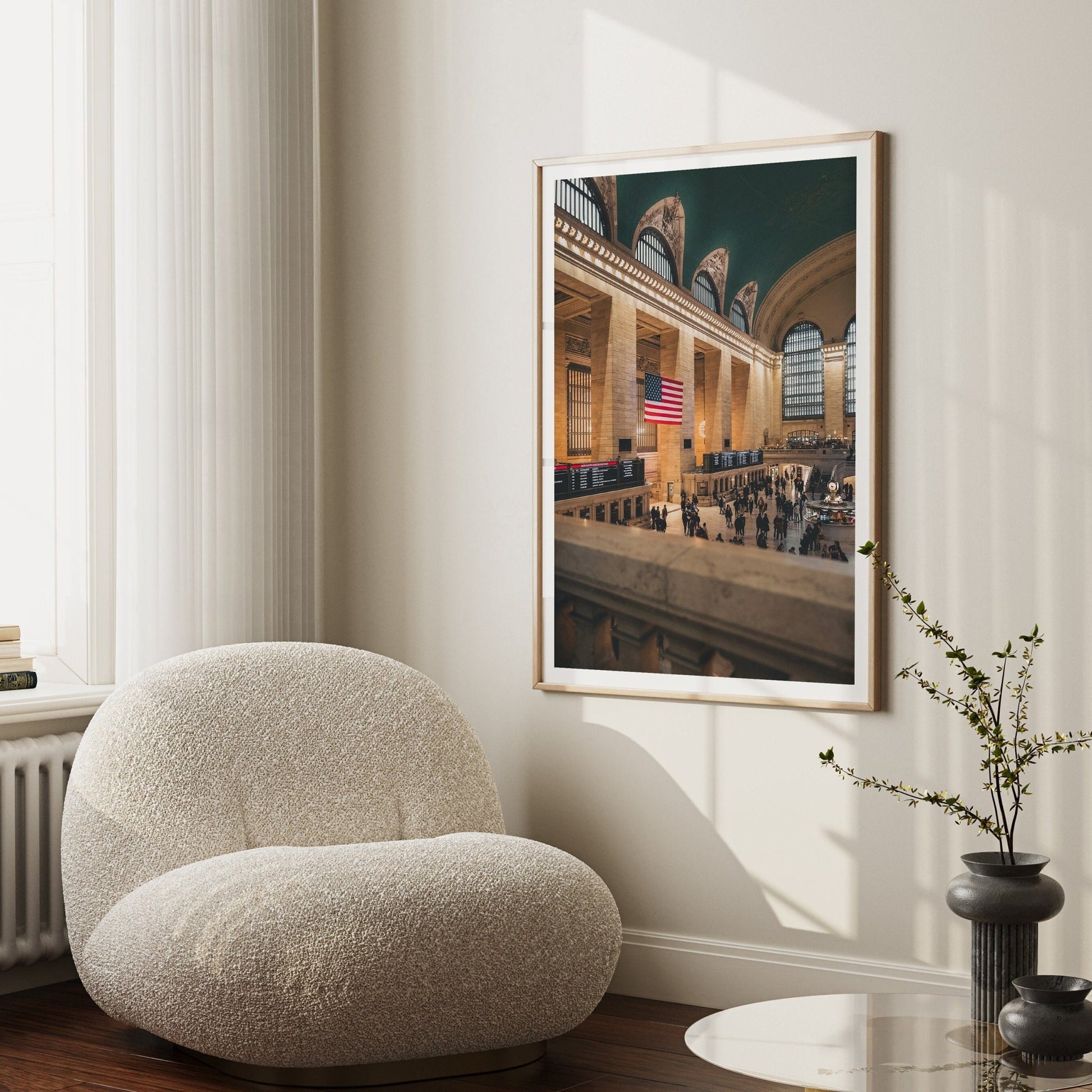 Cozy room with a soft white chair, minimalist decor, and a framed Grand Central photo with an American flag.