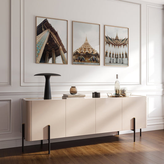 A modern room with a beige sideboard, black vase, Grand Palace photos on the wall, and wooden flooring.