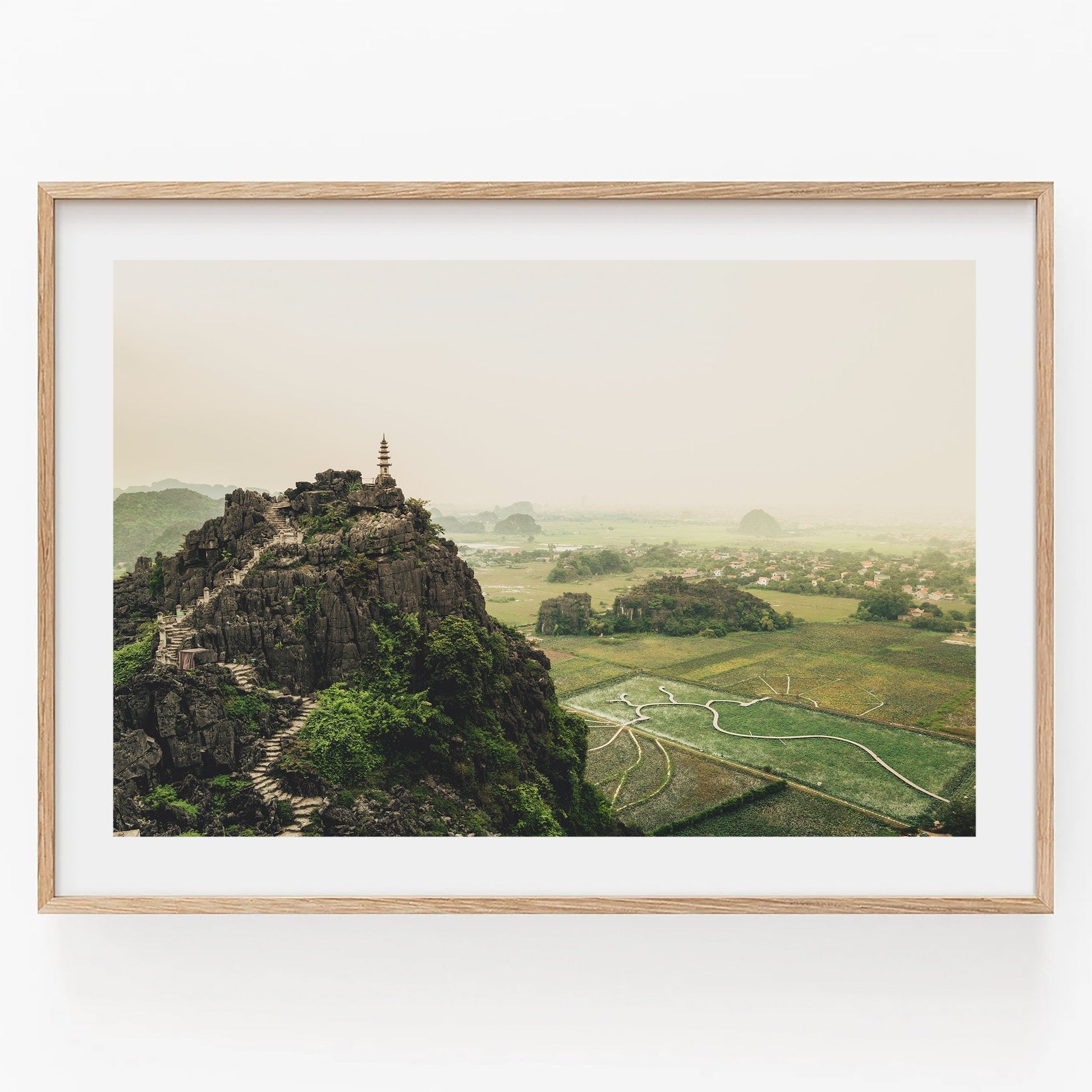 Hang Mua Peak II: A pagoda atop a rocky hill with winding stairs, overlooking misty fields and distant hills.