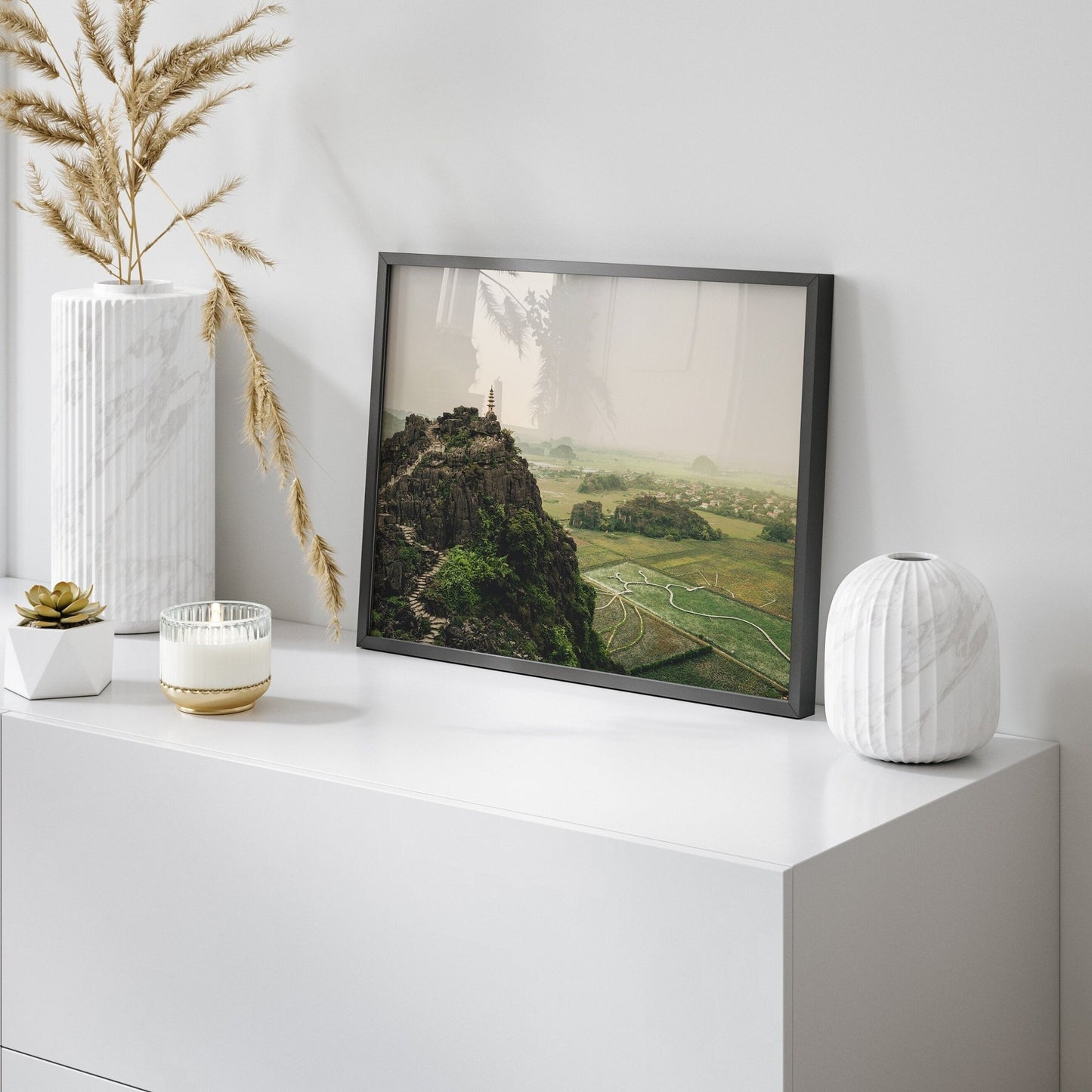 Framed Hang Mua Peak II photo on a modern white desk with vases and candles.