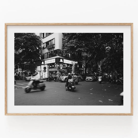 Framed photo titled Hanoi Intersection Black and White featuring motorcycles and cars on a busy street.