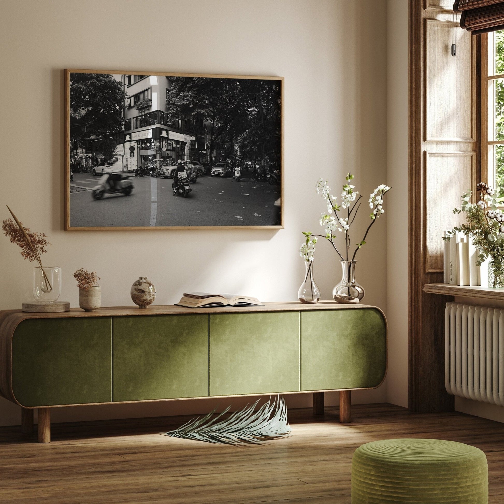 A cozy room featuring a green sideboard, potted plants, and the Hanoi Intersection Black and White photo on the wall.