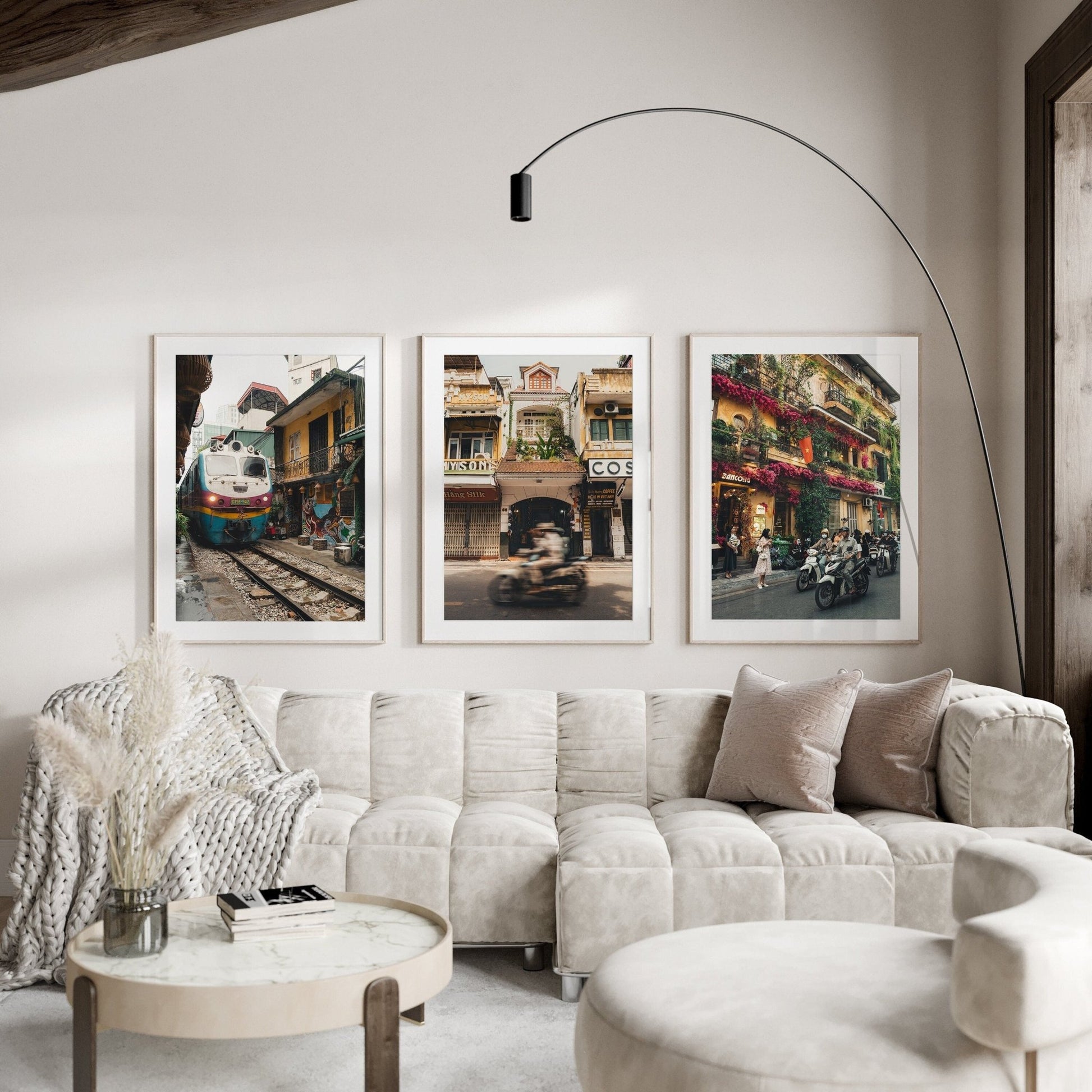 Modern living room with a curved sofa, round table, and Hanoi Streets - Set of 3 cityscape photos on the wall.