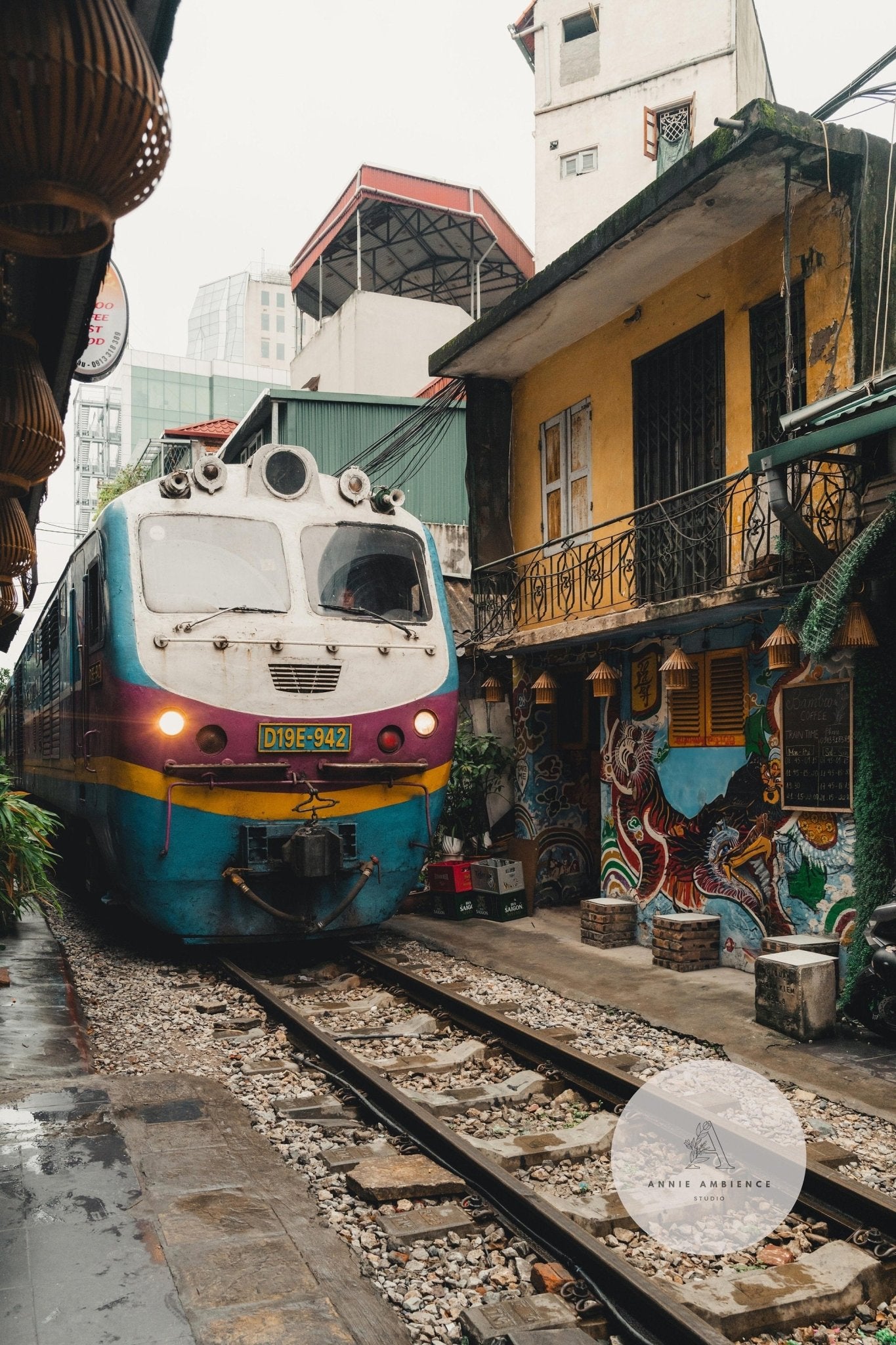 Colorful train passes through narrow street next to a yellow building in Hanoi under the Hanoi Streets - Set of 3.