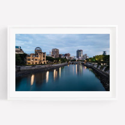 Framed photo titled Hiroshima Peace Memorial, featuring a river lined with modern buildings and a dome structure under a cloudy sky at dusk.