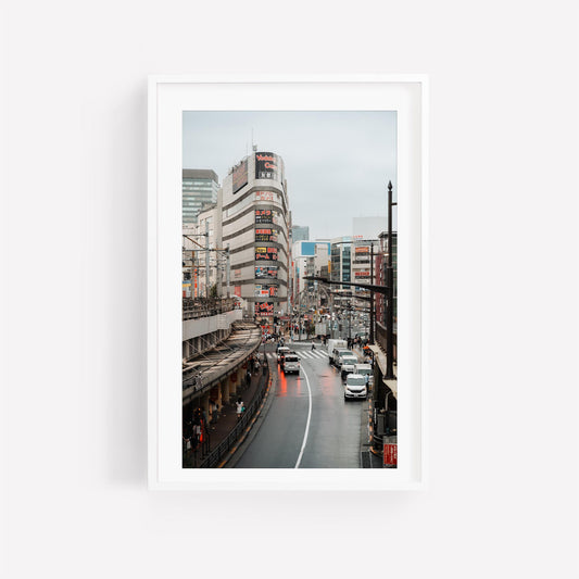 Framed Ueno Cityscape photo on white wall, capturing a bustling street with cars, buildings, and billboards.