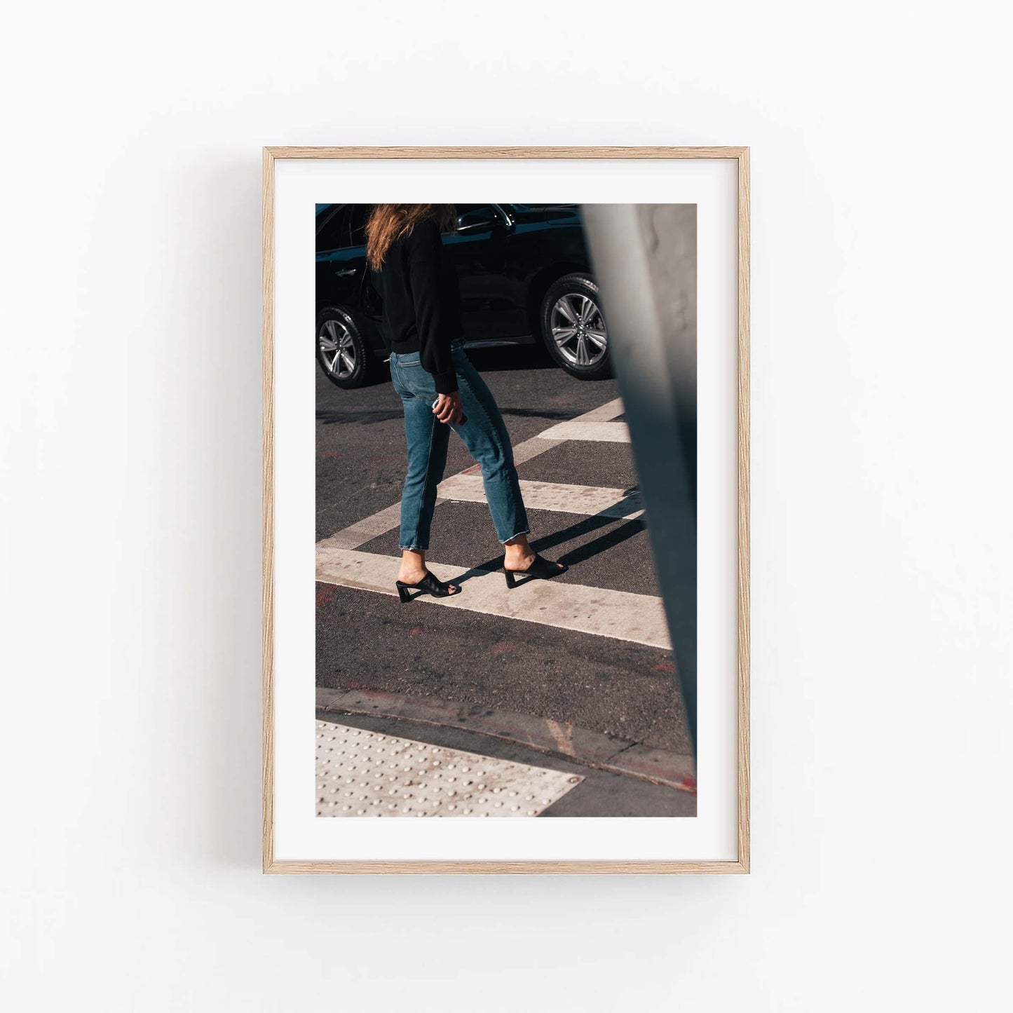 Framed photo Sunday Chic: Person in jeans and heels crossing a street, with a car in the background.