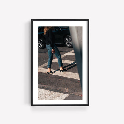 Framed Sunday Chic photo of a person crossing the street in jeans and heels with a car in the background.