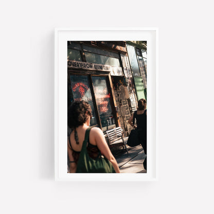 Framed photo of Overthrow Boxing Club with two people walking past an old building with a bench and posters.