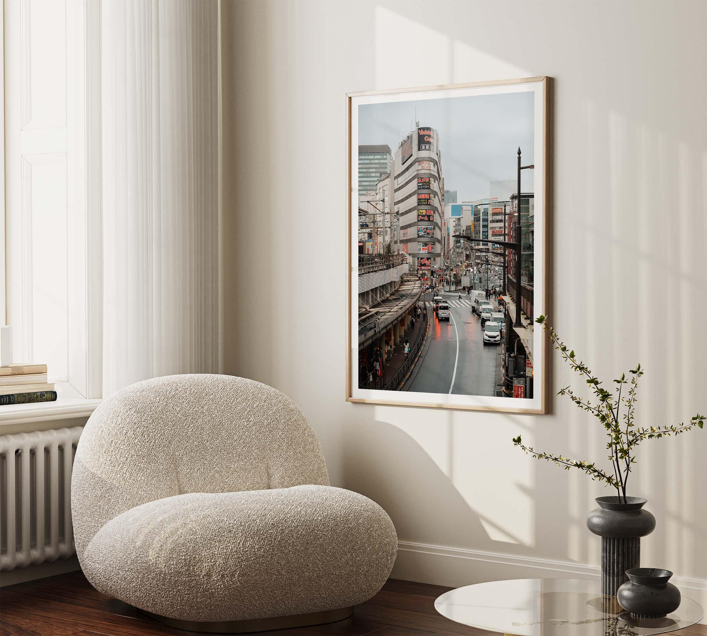 Cozy room with a plush chair and Ueno Cityscape photo on the wall. Light pours in through large windows on the left.