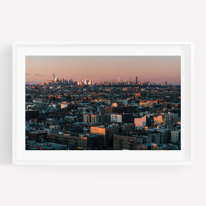 Framed photo titled Skyline From Brooklyn featuring a city skyline with buildings under a pink sunset sky.