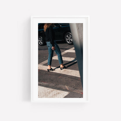 A framed photo titled Sunday Chic shows a person in jeans and heels crossing a sunny street with a black car behind.