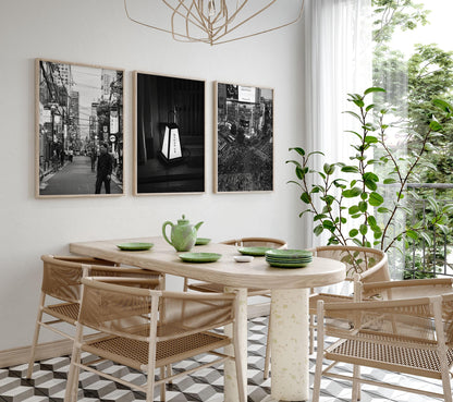 A dining room with a wooden table, wicker chairs, green tableware, plant, and Japanese Cities Black and White - Set of 3 photos.