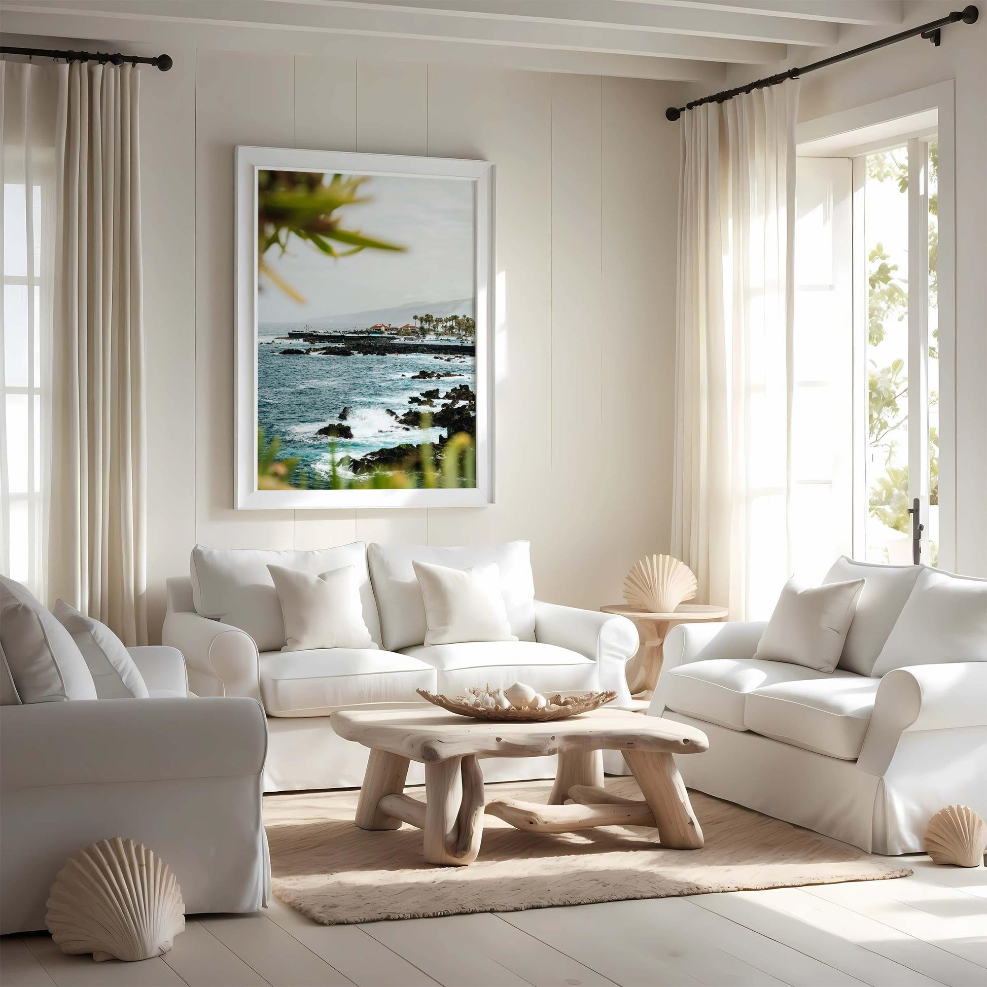 Bright living room with white sofas, wooden table, and the Coastal Glimpse ocean photo on the wall.
