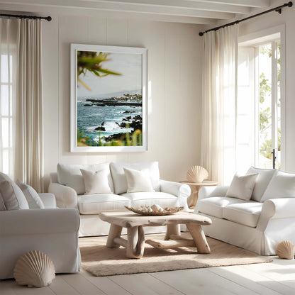 Bright living room with white sofas, wooden table, and the Coastal Glimpse ocean photo on the wall.