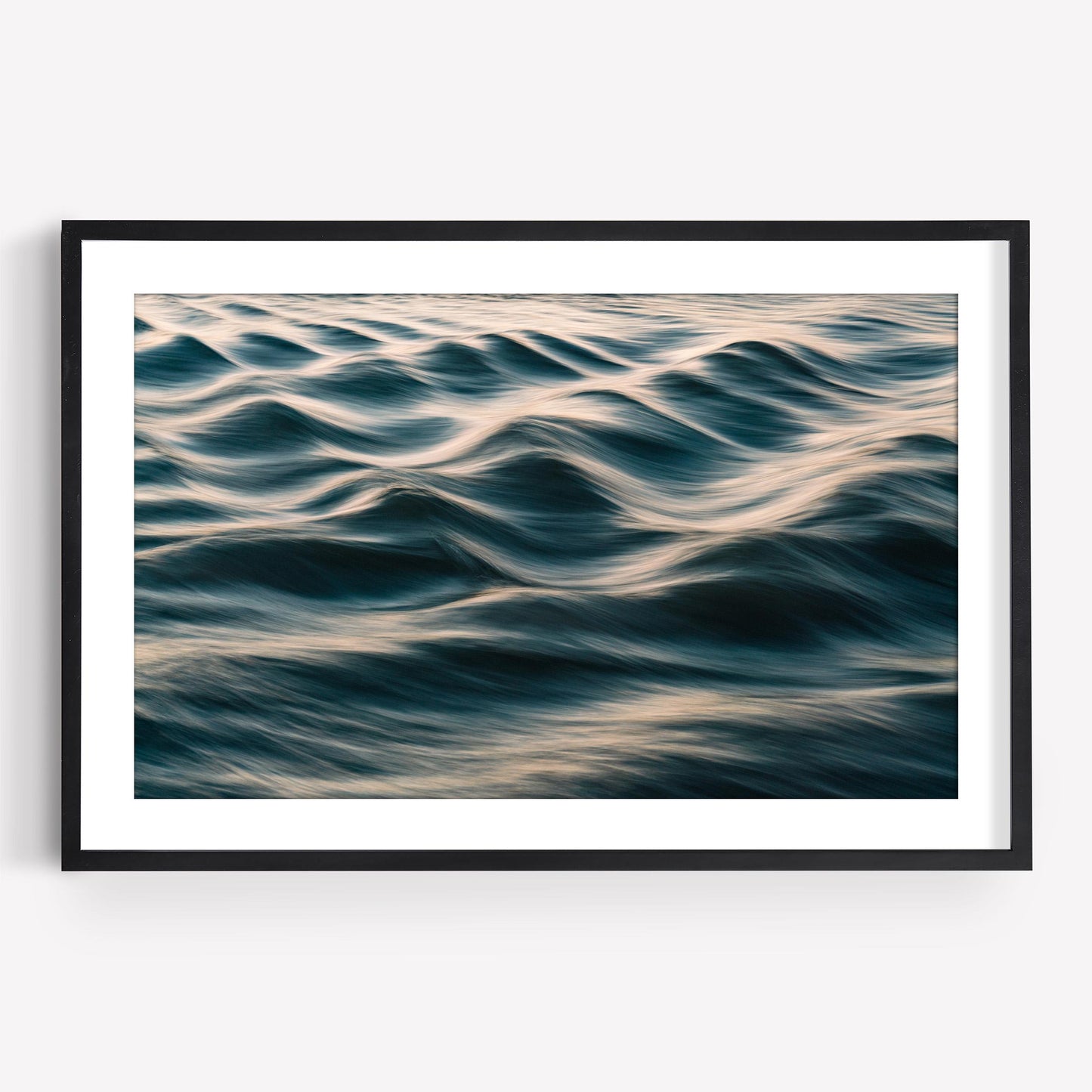 “Silk Waves” abstract photo of rippling ocean with soft golden light, in a sleek black and white frame.
