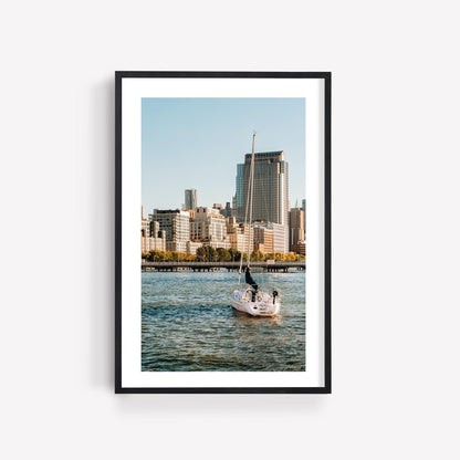 Framed photo "Tribeca Waters" shows a sailboat on water with a city skyline and tall buildings in the background.