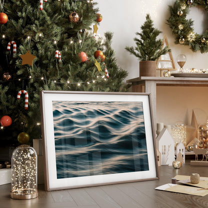 Silk Waves" ocean photo framed, displayed on floor by decorated Christmas tree with fairy lights and holiday decor.