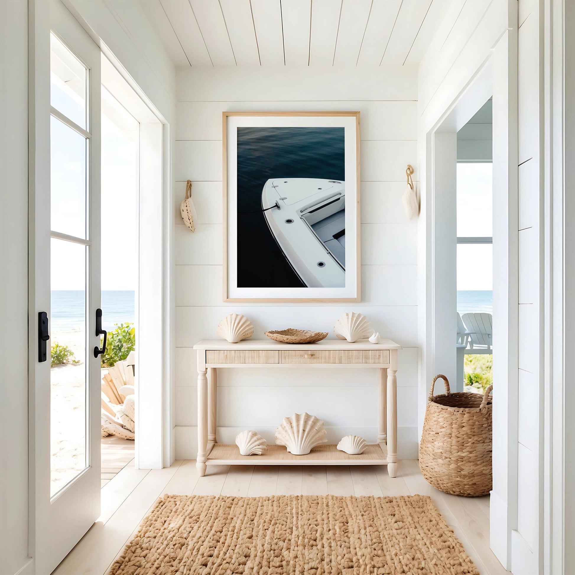 Bright beachy entryway with a console table, seashells, and the Blue Hour Mooring boat photo overlooking the ocean.