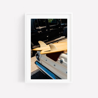 Vintage Surf Ride: Two surfboards sit atop a vintage white car parked beside a black vehicle in the sun.