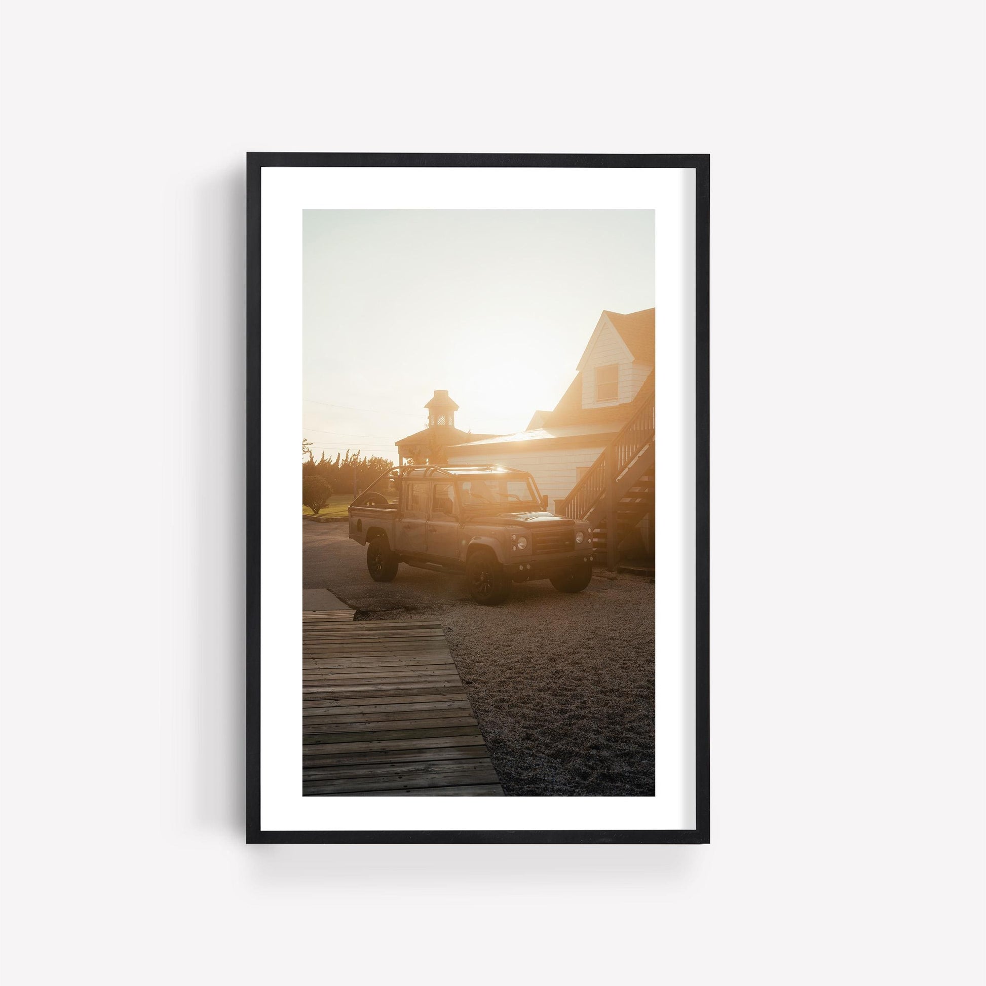 Golden Hour Defender: A framed photo of a vintage SUV at sunset, sunlight shining behind the house.