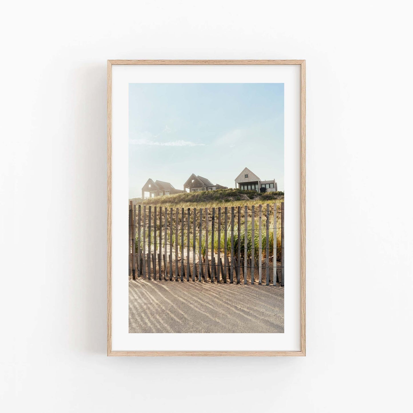 Summer Homes“ framed photo: coastal houses on grassy dune behind fence under a clear blue sky.