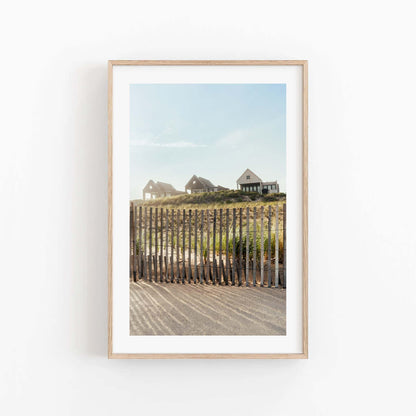 Summer Homes“ framed photo: coastal houses on grassy dune behind fence under a clear blue sky.
