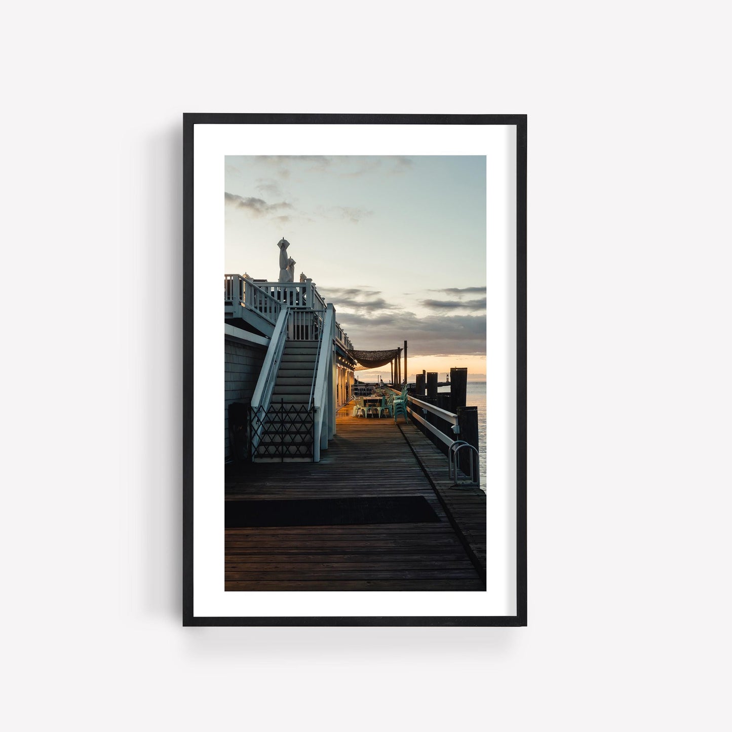 Framed photo, “Dockside Evening”: wooden boardwalk by water at sunset, with empty chairs and stairs on the left.