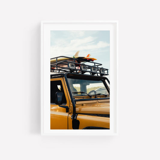 Surf Roadtrip: A yellow SUV with roof rack & surfboard, in a modern white frame against a white background.