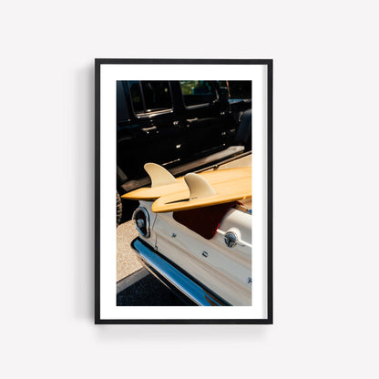 Vintage Surf Ride: Framed photo of surfboards on a classic white car beside a black vehicle.