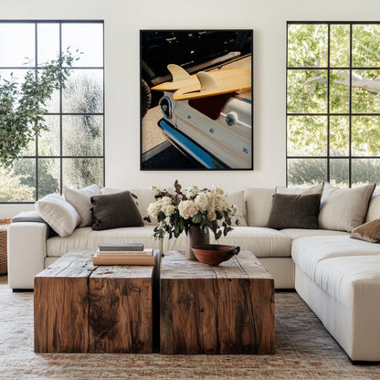 Bright living room with white sectional, rustic wood tables, flowers, and Vintage Surf Ride wall art.
