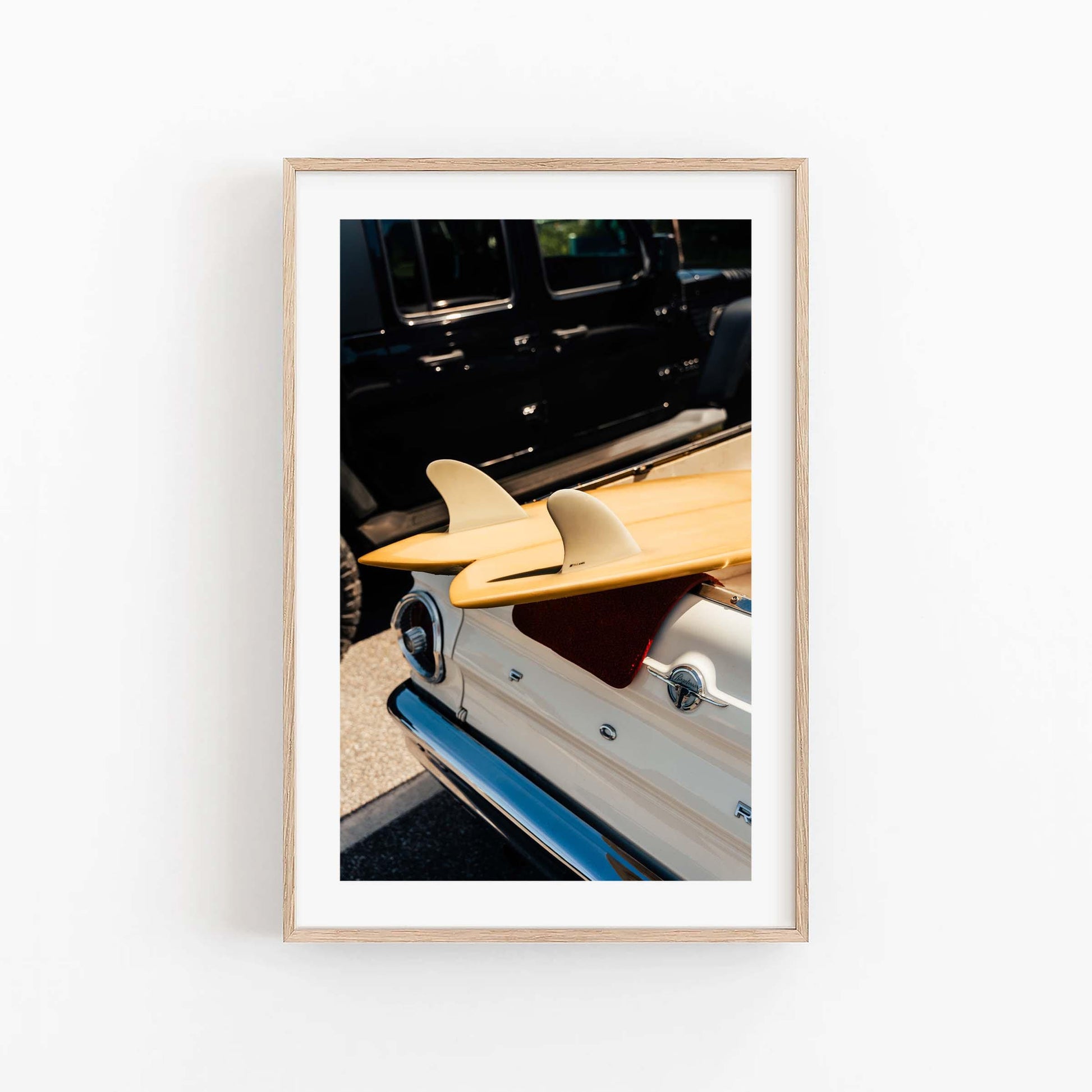 Vintage Surf Ride: Framed photo of surfboards on a white vintage car, parked next to a black vehicle.