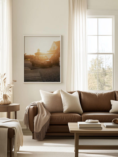 Sunlit living room with Golden Hour Defender sofa, beige pillows, a blanket, and framed wall art above.