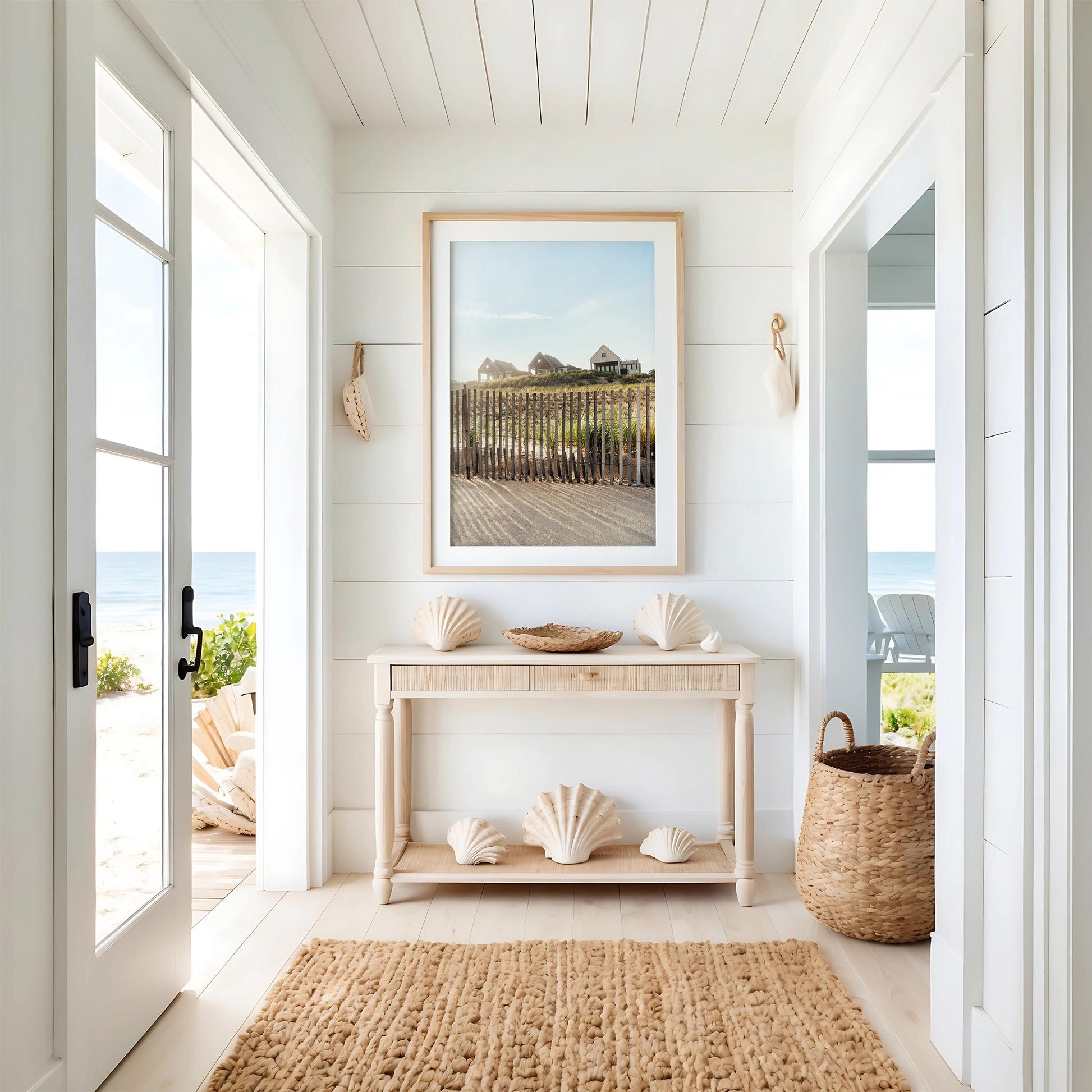 Create a bright coastal entryway with Summer Homes—a console table, large seashells, basket, rug, and ocean view.