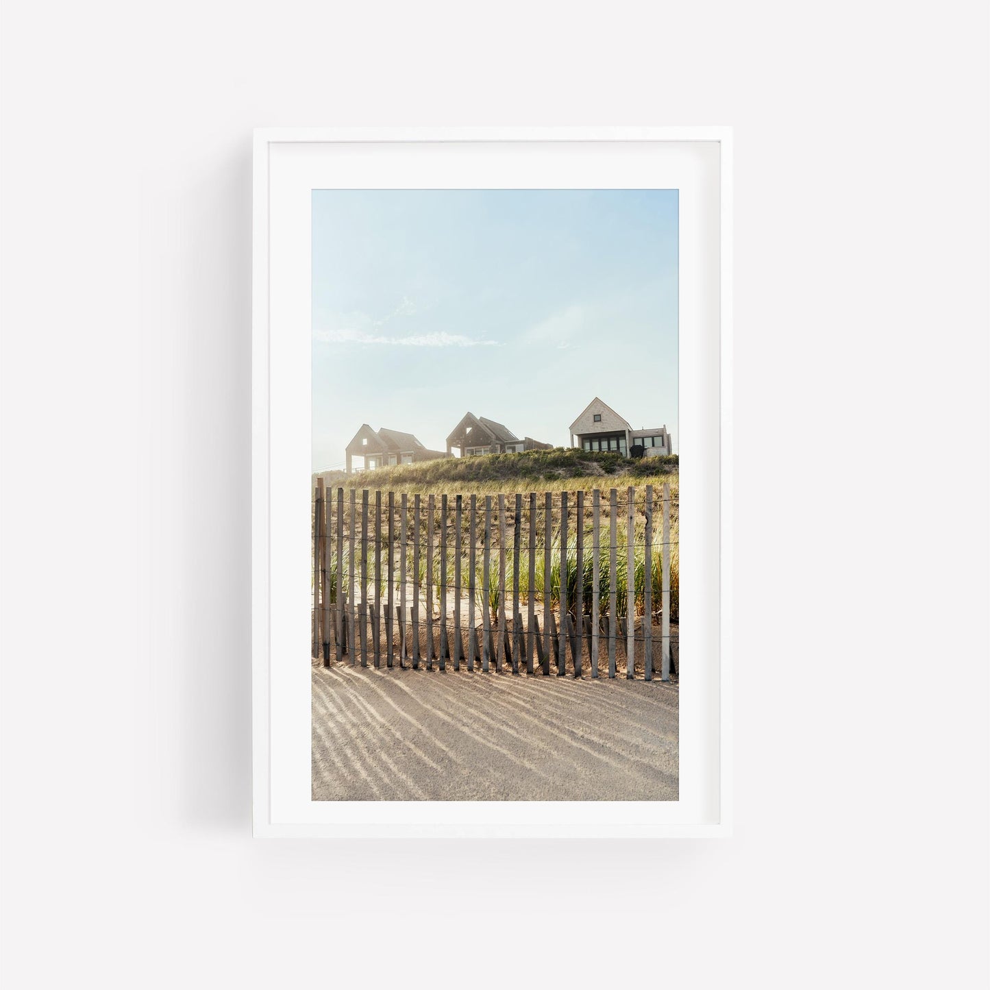 Summer Homes: Three houses on a grassy hill behind a fence under blue sky, framed in white.