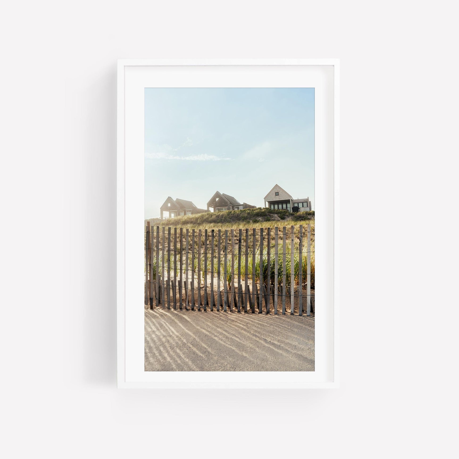 Summer Homes: Three houses on a grassy hill behind a fence under blue sky, framed in white.