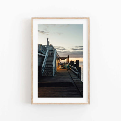 Dockside Evening: Framed photo of a wooden dock at sunset with stairs, railings, and tranquil water in the background.