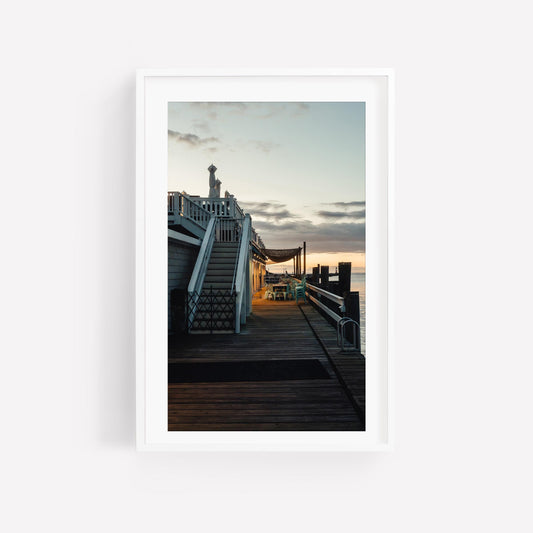 Dockside Evening: Framed photo of a boardwalk at sunset with stairs and seating by the water.