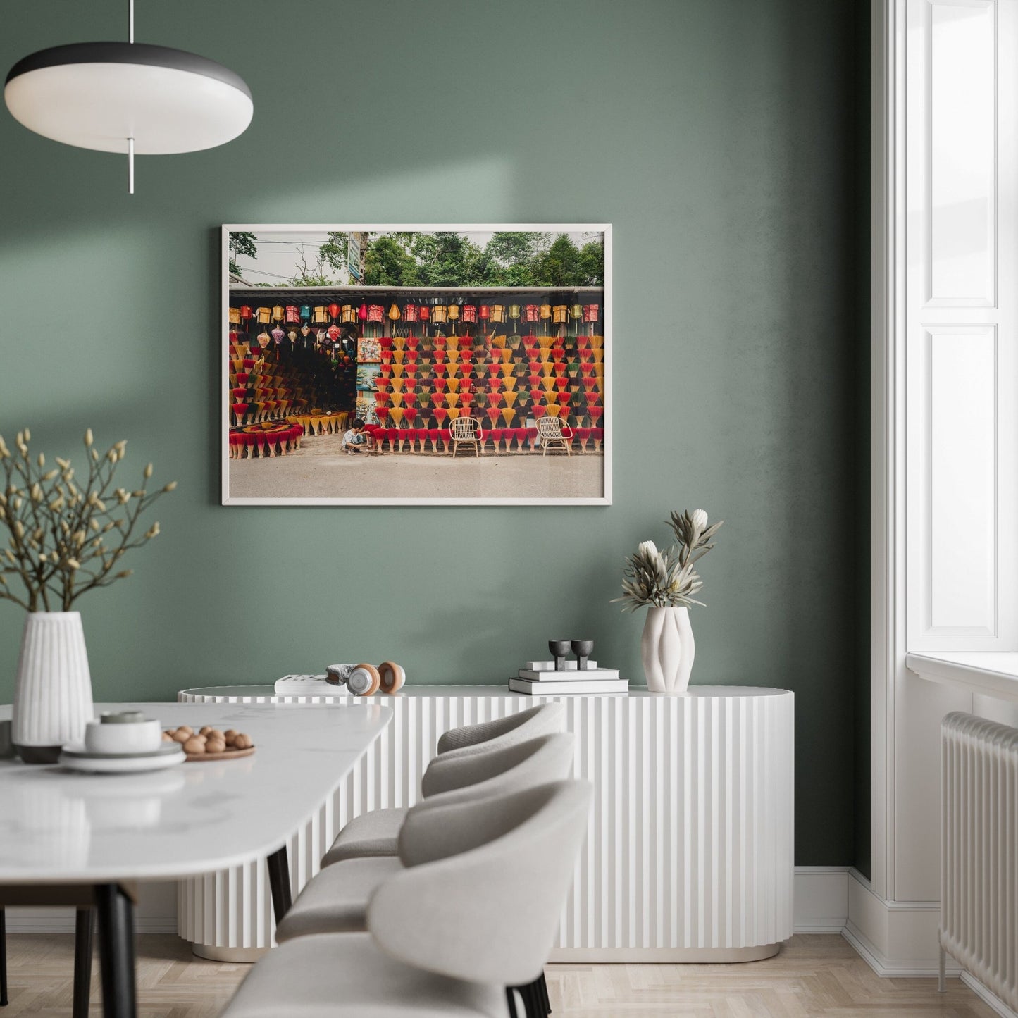 Modern dining room with Incense Shop decor, green wall, framed art, white furniture, and white chairs around a table.